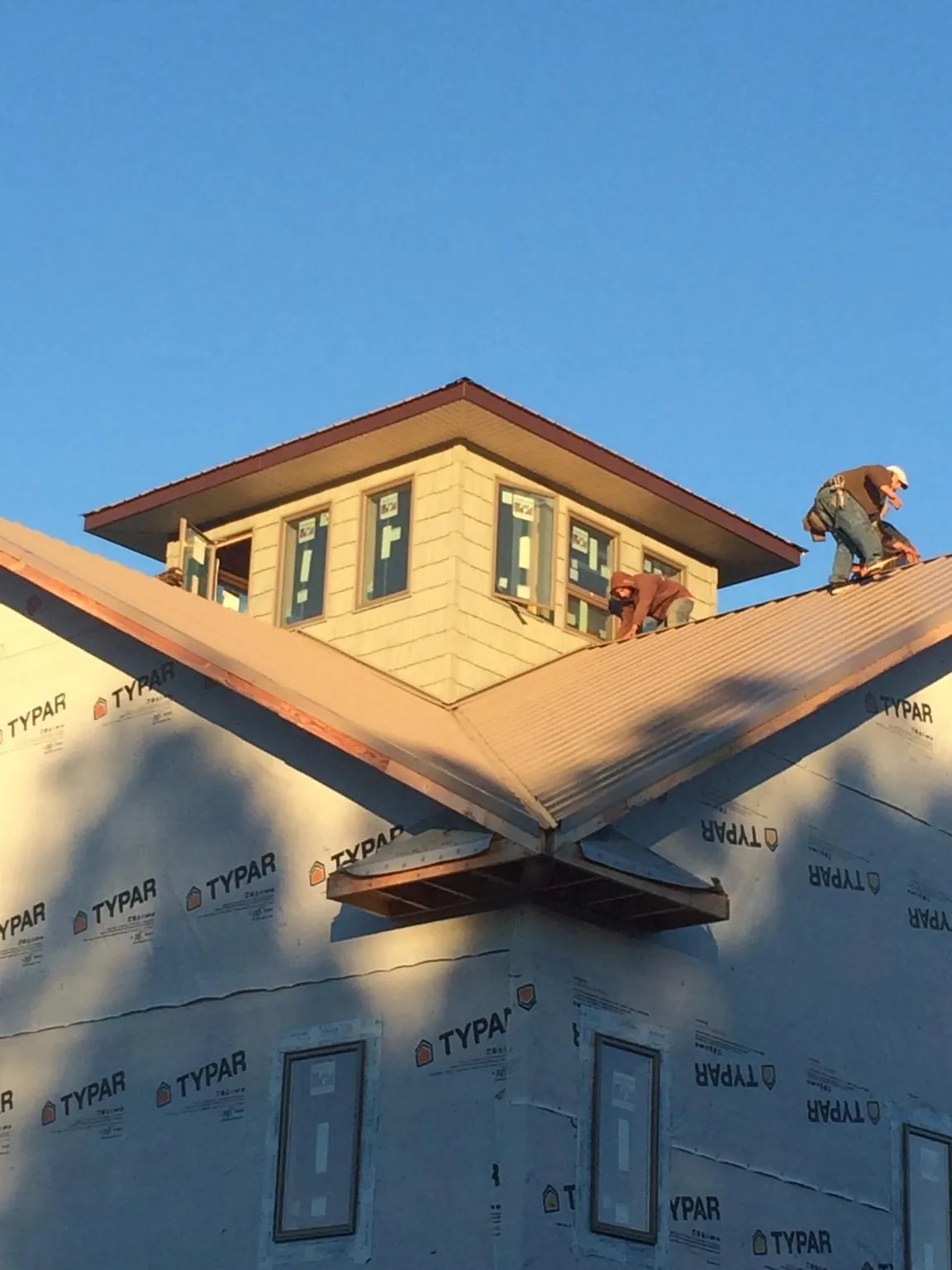 Roofers working around a rooftop cupola on a new metal roof at sunset — Roof Waterproofing in Sunset by Roofing Brothers